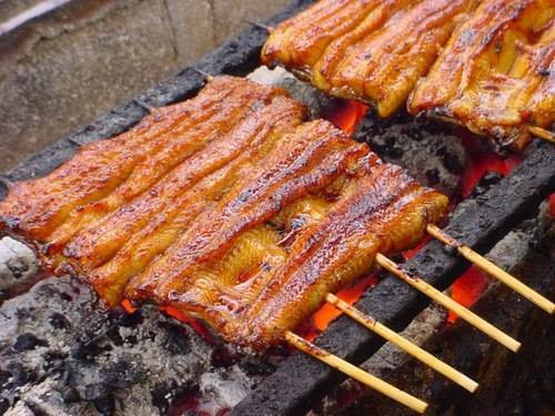 Lươn nướng Unagi. Lươn là thực phẩm giàu dinh dưỡng hơn một số loại hải sản như tôm, cua,.. lại không bị ngấy như thịt. Có thể xem lươn biển (Unagi) là thực phẩm thanh nhiệt tuyệt vời ở Nhật. Những miếng lươn chưa tẩm gia vị được nướng trên bếp than từ 5-10 phút để mỡ lươn chảy ra giúp thịt mềm và không bị khô. Các miếng thịt lươn sẽ được trở mặt liên tục đến khi vàng đều và không bị cháy khét. Ảnh: monnhatban