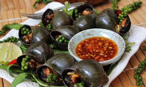 Ốc nướng tiêu xanh vừa là món ăn vặt, vừa là món nhậu được ưa chuộng của người dân nơi đây. Ốc bỏ lên vỉ than nướng, sau khi thấm hơi nóng thì tách lớp mài. Lúc này bỏ tiêu xay (hoặc muối tiêu), đến khi thấy nước ốc sôi là có thể gắp ăn. Trước khi nướng, có thể tẩm ướp sẵn ốc với gia vị giúp món ăn đậm đà hơn. Món này ăn kèm với nước mắm ớt. Ảnh: tourdulichmientay