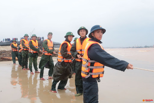 Vừa qua, ngày 8/10, tàu Vietship 01 khi đang cơ động tránh trú bão đã bị sóng đánh cuốn trôi ra khu vực phao số 0 ở biển Cửa Việt, cách bờ khoảng 400m. Nhanh chóng, các chiến sĩ của lực lượng quân sự Quân khu 4, Ban chỉ huy Quân sự tỉnh Quảng Trị, Quân chủng Hải quân, Bộ đội biên phòng đã được triển khai để nghĩ cách cứu nhiều thuyền viên đang bị mắc kẹt trên con tàu giữa biển khơi, dễ dàng bị nhấn chìm và cuốn trôi đi bất cứu lúc nào, tính mạng luôn bị đe dọa nghiêm trọng. Ảnh: Bộ đội đang cố cứu hộ những người mắc kẹt trên tàu Vietship 01.