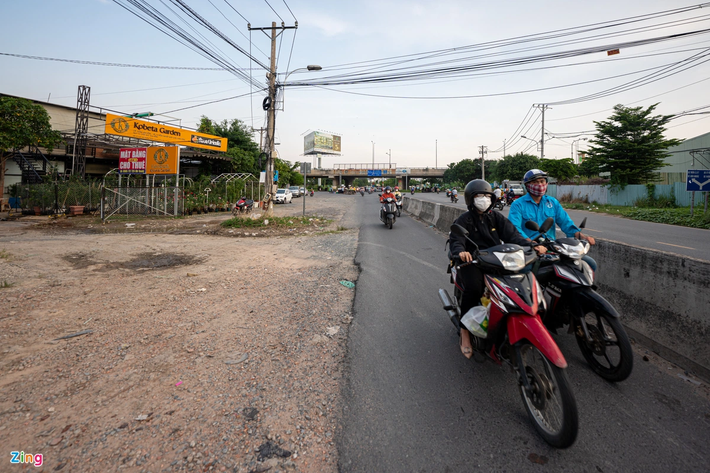 Trong khi đó, đoạn qua cầu vượt Đỗ Xuân Hợp (nút giao cao tốc TP.HCM - Long Thành - Dầu Giây), mặt đường đã được mở rộng, nhưng vẫn chưa thể kết nối. Trong ảnh, bên phải là làn xe máy hướng về xa lộ Hà Nội chỉ rộng gần 2 m, trong khi bên trái vẫn trải đá dăm, cỏ dại mọc và các trụ điện nơi đây chưa được di dời.