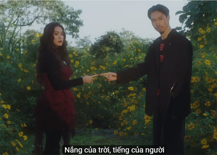 MV mở đầu bằng hình ảnh Hoàng Thùy Linh và Đen Vâu chạm ngón tay vào nhau tại rừng hoa dã quỳ thơ mộng. (Ảnh: Cắt từ clip)