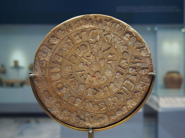 Đĩa Phaistos được phát hiện bởi nhà khảo cổ học người Ý Luigi Pernier vào năm 1908 tại cung điện Minoan của Phaistos, chiếc đĩa được làm bằng đất sét nung và chứa các biểu tượng bí ẩn có thể đại diện cho một dạng chữ tượng hình chưa được biết đến. Theo các nhà khảo cổ, nó có thể ra đời vào thế kỷ 2 TCN. Nguồn: C messier/Wikimedia Commons.