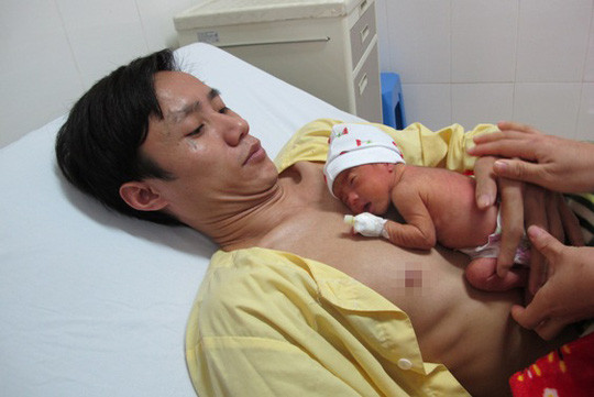 Anh Thiều Văn Thương hạnh phúc ôm con vào lòng. "Ngày đầu, khi bác sĩ hướng dẫn ấp con, tôi cũng lóng ngóng lắm, chỉ sợ làm rơi con. Nhưng khi con nằm trên ngực, chạm với da của con cảm giác như đang cùng nhịp thở với mình, thấy gắn bó, thiêng liêng lắm"- anh Thương chia sẻ.