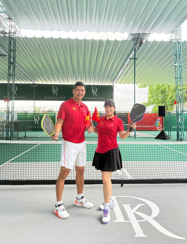 Vợ chồng Bình Minh - Lê Anh Thơ chụp ảnh trên sân Pickleball, cầm cờ đỏ sao vàng hướng về đại lễ 30/4. Ảnh: FB Le Anh Tho