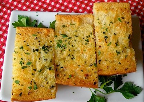 Tắt bếp, cho tỏi băm, mùi và tiêu vào đảo đều trong bơ đang nóng. Sau đó phết lên 1 mặt từng miếng bánh mỳ đã cắt. Xếp vào nồi bật nhiệt 180 độ C, nướng trong 10 phút. Ảnh: doisongphapluat.com.