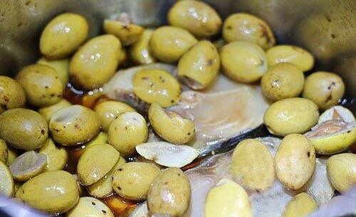 3. Trám om cá. Nguyên liệu: Cá tùy loại, trám, tương, gia vị. Trám đem ngâm nước khoảng một đến hai giờ rồi rửa lại, chà cho sạch nhựa. Nước đun sủi lăn tăn, cho trám vào chìm dưới đáy nồi, đảo đều rồi nhắc xuống đậy kín vung cho nguội dần, vớt ra cho từng quả lên mặt thớt, sau đó lấy dao tách cùi, bỏ hột. Ảnh: Tourgiare.vn.