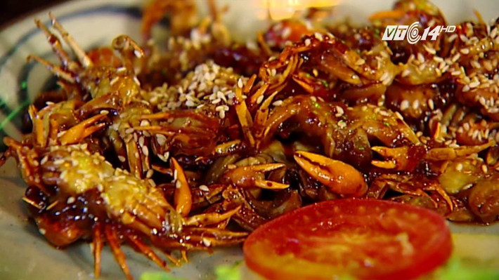 Phi thơm 3 thìa dầu ăn với tỏi, hành băm nhỏ, gừng thái chỉ và một ít ớt bột để món ăn có màu sắc hấp dẫn hơn; Sau đó trút cua đồng vào từ từ, đảo nhanh tay với lửa vừa. Ảnh: youtube.com.