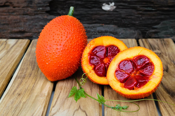 2. Bánh gấc: Bột nếp nước, đậu xanh, mỡ phần, mứt bí, hạt sen, dừa sợi, gấc, mè trắng, đường, vani, dầu ăn, lá chuối. Gấc bổ đôi, moi lấy hạt, trộn đều với ít rượu trắng cho ra phần thịt đỏ, bóc bỏ hạt gấc. Ảnh: HelloBacsi.com.