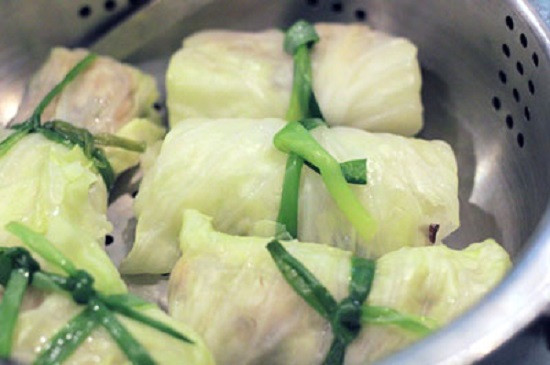 Trộn mộc nhĩ, miến, một thìa nhỏ muối, một ít hạt tiêu, hành khô thái nhỏ vào bát thịt băm, ướp khoảng 15 phút. Chần sơ hành lá, vớt hành ra âu nước lạnh. Cho bắp cải vào luộc khoảng 3 phút. Dùng thìa múc một ít hỗn hợp thịt đặt lên lá bắp cải. Dùng tay gấp mép và cuốn tròn lại, dùng một cây hành lá cột lại, làm cho hết phần thịt và phần bắp cải. Ảnh: toinayangi.vn.