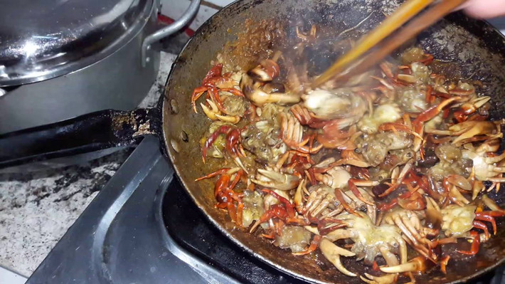 Cho nước me, bột năng hòa tan, nước hột điều đỏ vào, cho thêm chút nước mắm, muối, bột ngọt. Sau đó cho cua vào trộn đều lên cho thân cua và càng cua ngấm hết gia vị. Ảnh: youtube.com.