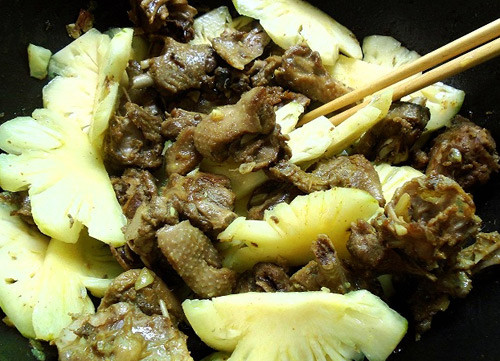 Ướp thịt với hành tím, tỏi băm nhuyễn, 1 muỗng bột canh, 1 muỗng màu dầu điều, 1 muỗng cà phê ớt bột. Ướp trong khoảng 30 phút. Dứa gọt vỏ, bỏ sạch mắt dứa, 1 nửa thái thành miếng vừa ăn, 1 nửa ép lấy nước cốt dứa. Ảnh: 24h.com.vn.