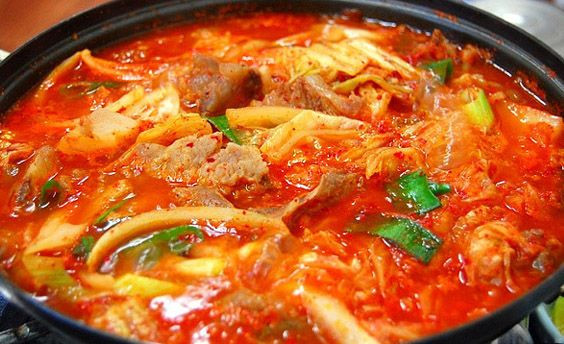 Cho kim chi vào đảo trong 1 phút sau đó thêm khoảng 120ml nước dùng vào. Đậy vung, đun trong 7 phút ở lửa vừa. thêm muối, đường vào, khuấy đều. Tiếp theo, cắt đậu hũ rồi dùng thìa dầm nhỏ đậu hũ ra. Ảnh: Thucthan.com.