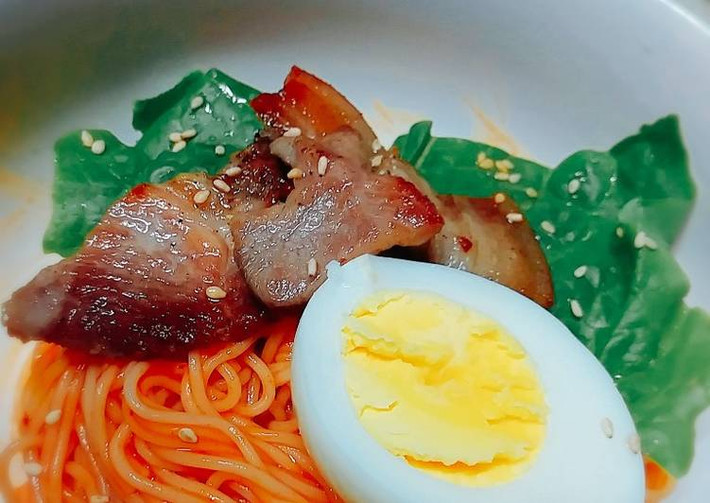 Trộn đều tất cả gia vị trên. Trứng sau khi bóc vỏ thái làm đôi. Trộn mì và nước sốt đều tay. Trang trí rau xà lách thịt ba chỉ và trứng sao cho đẹp mắt. Đừng quên rắc vừng lên. Ảnh: cookpad.com.