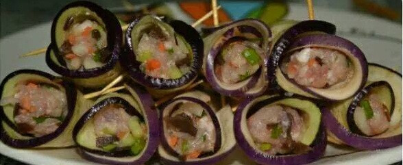 Dùng giấy bếp thấm khô miếng cà tím, sau đó cuộn tròn miếng cà tím rồi dùng que tăm ghim lại. Đặt tôm vào lồng cuộn cà tím, để đuôi tôm ló lên trên. Sau đó nhồi thịt cho đầy lên là được. Ảnh: Kheotay.org.