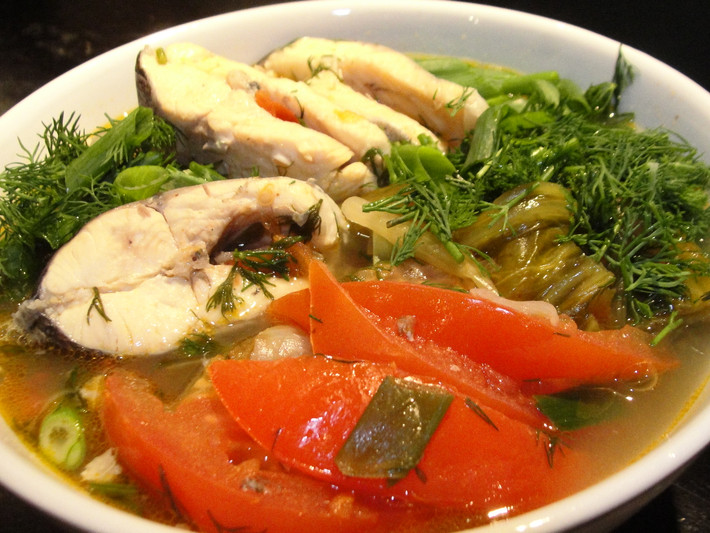 Nước sôi già thì có thể cho cá vào. Đun sôi trở lại và ninh nhỏ lửa 10 phút. Sau đó, bỏ sấu vào nấu thêm 10 phút. Sử dụng muôi thủng để vớt sấu lên rồi dùng thìa dằm nát. Cho lại sấu đã dằm vào nồi. Nêm gia vị vừa ăn. Đun sôi thêm 2-3 phút nữa. Cho hành, thì là vào là hoàn thành. Ảnh: Tinmoi.vn.