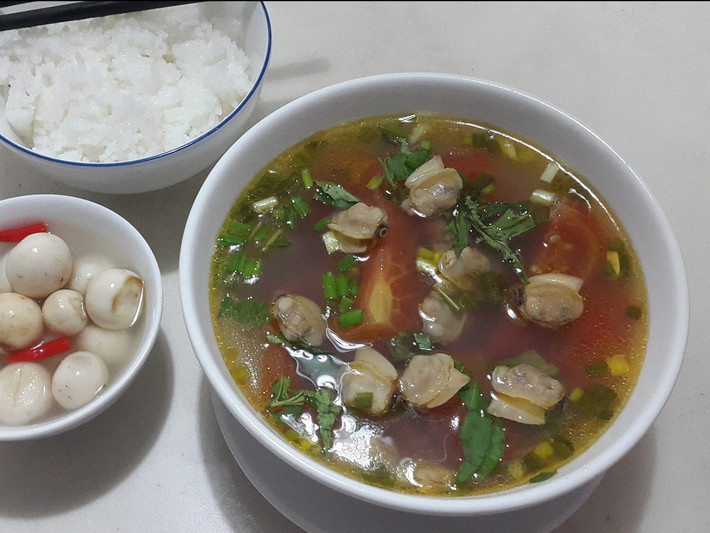 Bắt nồi lên bếp, cho ít dầu ăn vào đợi dầu nóng bỏ hành vào phi thơm lên cho ngao vào đảo qua lại cho thơm. Tiếp tục cho cà chua vào đảo qua rồi cho hết nước luộc ngao vào nấu cho sôi lên. Bỏ hết sấu vào đợi nước sôi lên lại rồi nêm nếm cho vừa ăn và bỏ hành lá và thì là vào rồi tắt bếp. Ảnh: Lamthenao.com.