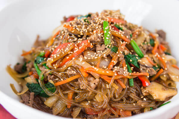 Tiếp theo, cho miến, nước tương, muối, hạt nêm, đường trắng vào, trộn đều, tắt bếp ngay. Rắc mè trắng rang lên trên. Cho món ăn ra đĩa và dùng nóng. Ảnh: Emvaobep.com.