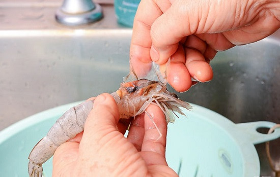 Sau đó, lấy tôm rửa sạch, bóc bỏ vỏ ở phần thân, dùng dao nhọn rạch nhẹ để khều bỏ chỉ lưng, chừa lại phần đuôi cho đẹp. Dùng kéo cắt gọn phần chân và râu tôm rồi xóc với rượu trắng. Ảnh: Womantoday.vn.