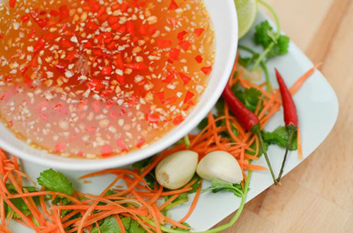 Pha nước mắm giấm để trộn nộm: 1 thìa nước mắm ngon, 2 thìa nước lọc, 1 thìa đường, 2 thìa nước cốt chanh. Cho các nguyên liệu gồm ớt, tỏi vào cùng mắm trộn đều. Ảnh: tinmoi.vn.