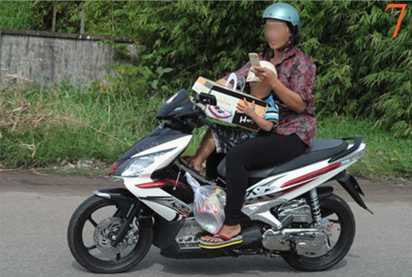 Người mẹ này đang vừa nghe điện thoại vừa chở con, lại con bắt con mang đồ cồng kềnh, thật sự quá đáng sợ. Ảnh: kenh14.vn.