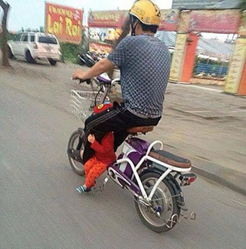 Không hiểu người cha này đang làm gì với đứa con mình. Xe đạp điện nhưng tốc độ cũng rất nhanh. Ảnh: eva.vn.