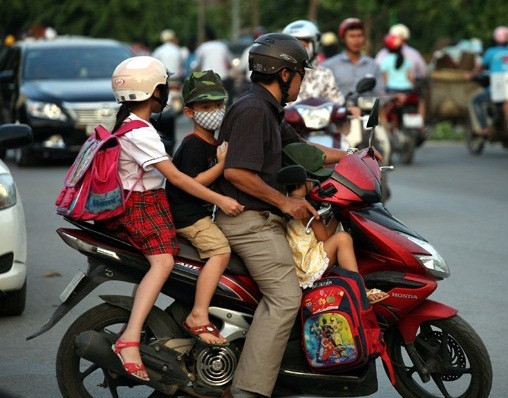 Chở ba trẻ đã là vi phạm luật giao thông, hai em bé còn không đội mũ bảo hiểm. Thật nguy hiểm. Ảnh: Xaluan.com.