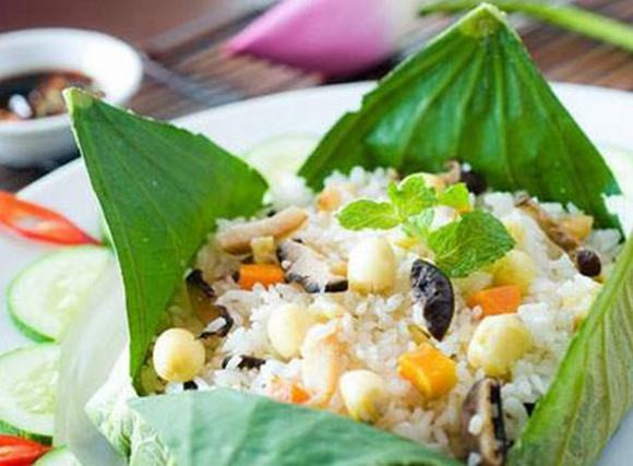 Cho cơm và cốm vào chảo nhẹ tay đảo qua một vài lần nữa. trải lá sen ra một mặt phẳng, cho cơm vào ở giữa, nhẹ nhàng gói lại các góc rồi mang đi hấp cách thủy trong vòng 5 phút là xong. Ảnh: tin247.com.