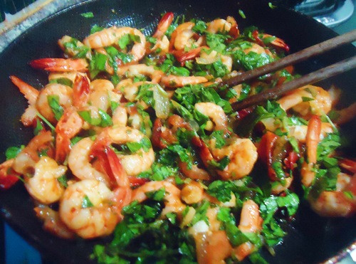 Lấy một chảo khác, cho dầu nóng thì trút hành tây, ớt và cà chua vào xào cùng lúc. Hòa tan hỗn hợp đường, nước cốt chanh, nước mắm trong một bát nhỏ. Từ từ đổ hỗn hợp này vào chảo tôm đang xào, đảo đều. Ảnh: eva.vn.
