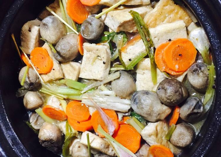 Nấm rơm làm sạch, ngâm nước muối, cà rốt cắt khoanh tròn, sả đập dập cắt khúc, hành tím cắt lát. Dùng nồi đất, đổ dầu cho nóng lên, rồi bỏ sả tới hành vào phi thơm, sau đó tới nấm. Nêm nếm vừa ăn với gia vị sau đó cho nước ngập nấm. Sau đó bỏ đậu phụ đã chiên vào. Nấu khoảng 5 phút cho sôi lên mới bỏ cà rốt cắt khoanh tròn vào nấu thêm 15 phút cho thấm ngon. Ảnh: cookpad.com.