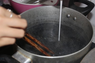 Cho bột gạo nếp lên chảo rang, để nhỏ lửa và đảo đều tay cho đến khi hạt gạo vàng thơm thì tắt bếp, để nguội rồi cũng mang xay hoặc giã. Sau đó, mẹ bầu cho bột sắn dây vào 1 chiếc bát và hòa cho tan. Ảnh: Webtretho.com.