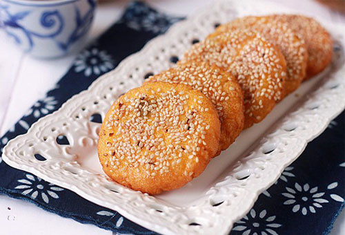 Cho bí đỏ đã xay nhuyễn ra tô, thêm bột nếp vào trộn chung, nhào cho đến khi nào bột thành 1 khối mịn, dẻo là được. Để bột nghỉ 30 phút. Lấy từng chút bột lên tay, ấn dẹt vào cho nhân đậu xanh, túm các mí bột lại và vo tròn. Ảnh: monngondelam.net.