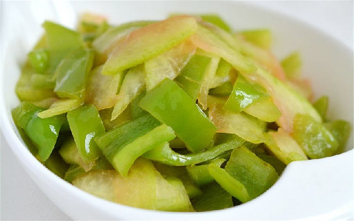 Ớt chuông xanh rửa sạch, thái miếng nhỏ vừa ăn. Làm nóng chảo dầu trên bếp, cho ớt chuông xanh vào xào. Tiếp đến cho cùi dưa vào xào, nêm muối vừa ăn xào chín tắt bếp rắc thêm tiêu cho thơm. Ảnh: Cooky.vn.