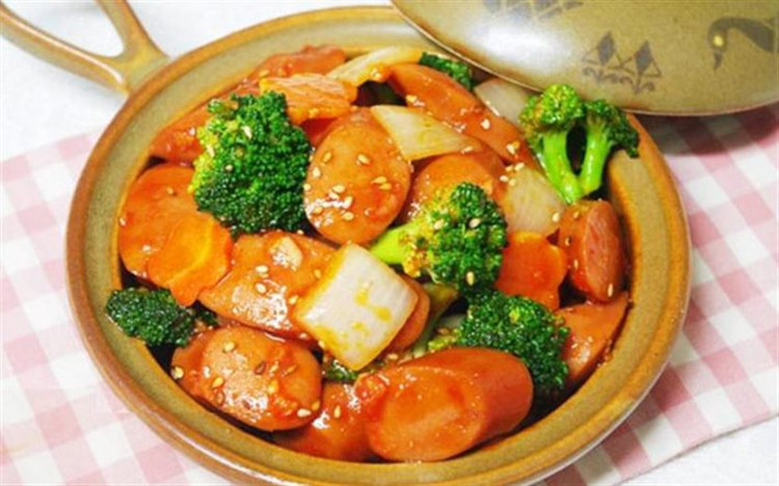 Bắc chảo lên bếp làm nóng chảo rồi cho 2 thìa dầu ăn sau đó cho hành tây, ớt chuông vào đảo đều. Tiếp tục cho xúc xích vào đảo mấy lượt thì cho nước sốt cà, dầu hào và đường vào. Xào đến khi nào nước sốt cạn là được. Ảnh: Cooky.vn.
