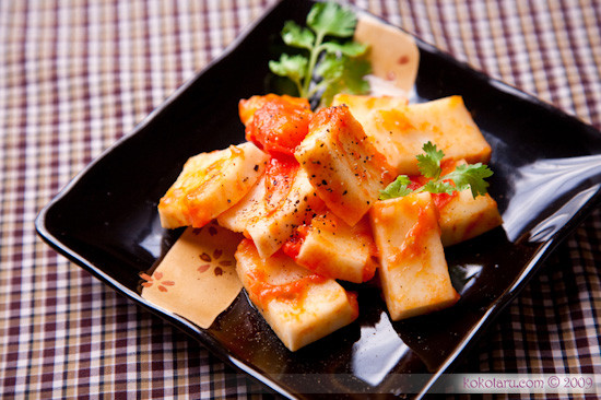 Phi thơm hành cùng với cà chua, khi cà chua nhừ thì cho một ít nước mắm, hạt nêm vào đảo đều rồi cho dừa vào om cùng. Đun lửa nhỏ cho tới khi nước cạn gần hết, miếng dừa ngấm đều với gia vị là được, rồi trộn ớt và hành tươi vào bắc xuống, cho ra đĩa. Ảnh: Kokotaru.com.