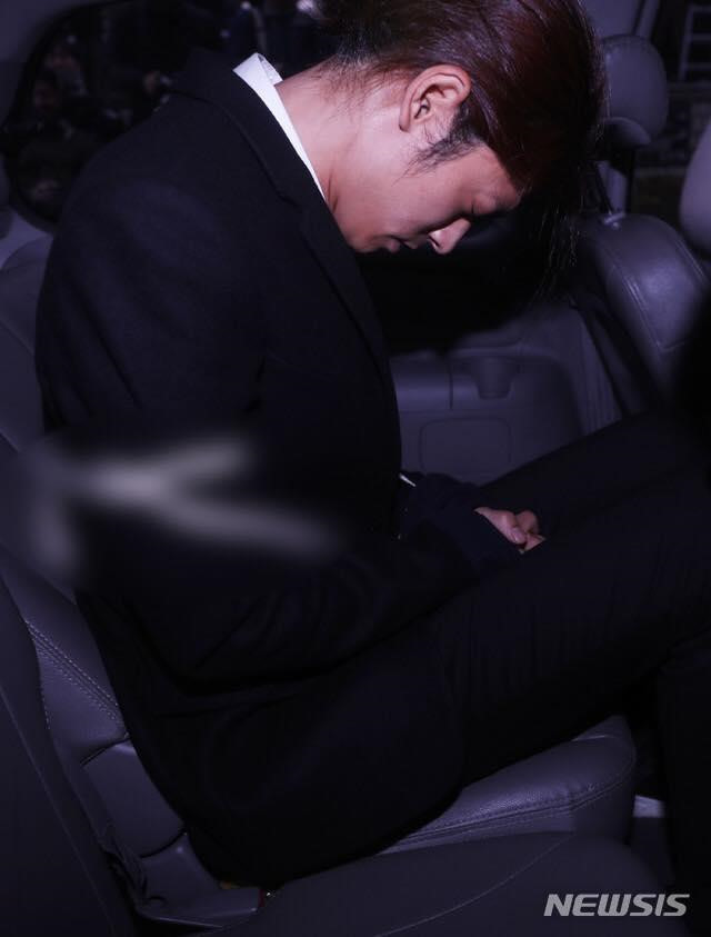 Jung Joon Young cúi gằm mặt khi bị cảnh sát áp tải về đồn. Ảnh: Newsis.