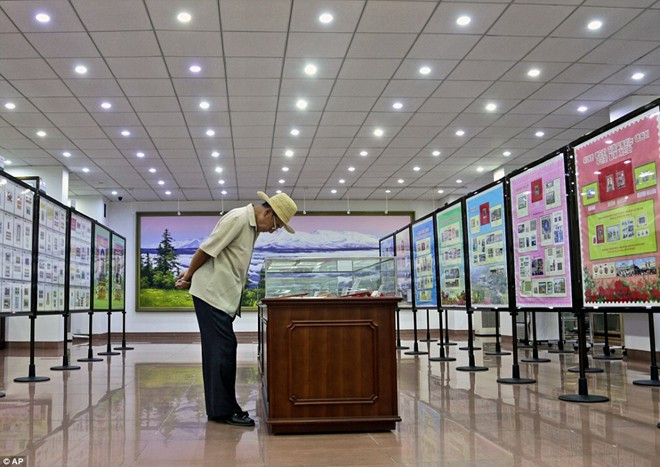 Một người đàn ông cúi nhìn những con tem trong tủ kính tại một cửa hàng. Ảnh: AP.