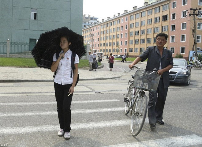 Người dân Bình Nhưỡng di chuyển qua đường. Phía sau họ là một chiếc xe ô tô bóng loáng. Tắc đường là chuyện hiếm khi xảy ra tại Triều Tiên. Ảnh: AP.