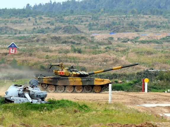 Và như chúng ta đã biết, bài thi của kíp lái số 1 của đội tuyển xe tăng Việt Nam xuất phát thứ hai với chiếc T-72B3 màu vàng là một bài thi vô cùng xuất sắc. Ở vòng chạy đầu tiên, pháo thủ ta đã tiêu diệt liên tiếp 3 mục tiêu bia số 12 mô phỏng xe tăng địch, dù cho gặp một số trục trặc nhỏ. Kết thúc vòng đầu với thời gian cực nhanh, chỉ dưới 10 phút. Ảnh: Xe tăng Việt Nam bước vào tiến bắn - Nguồn: QĐND.