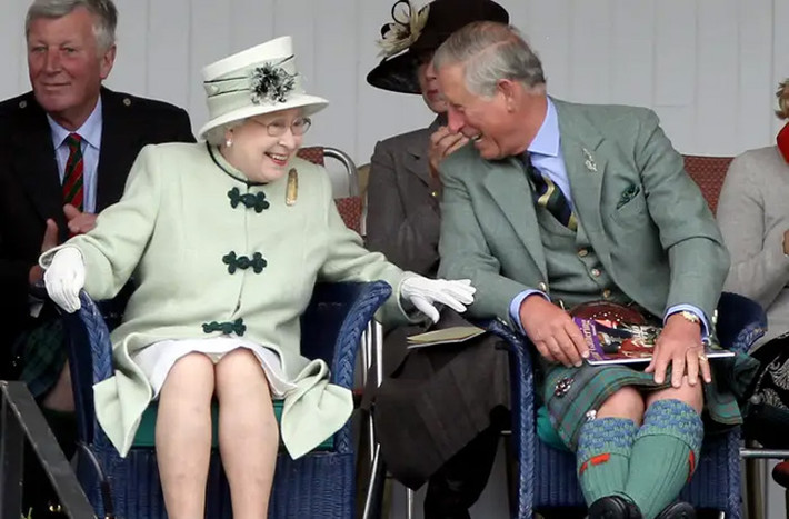 Trong lúc theo dõi cuộc thi kéo co tại Thế vận hội Braemar Highland ở Scotland, Nữ hoàng Anh Elizabeth II và con trai là Thái tử Charles chia sẻ một câu chuyện vui bên lề. (Nguồn ảnh: Insider)