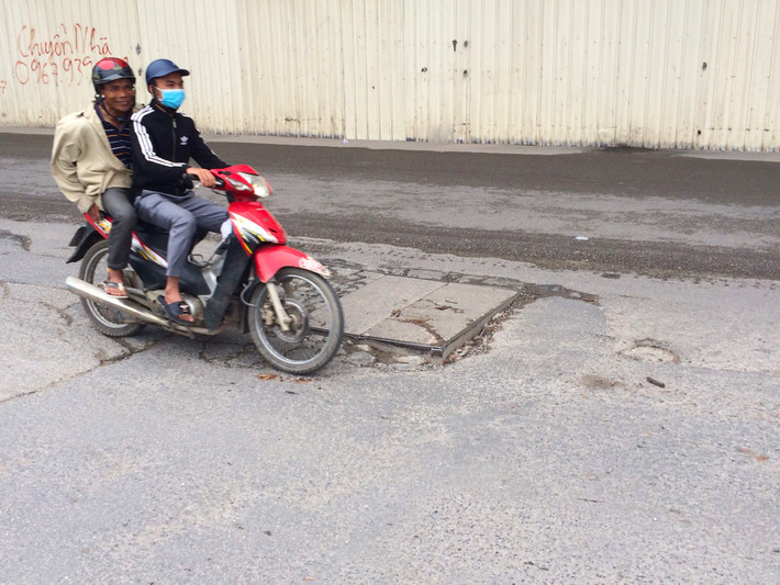 Nắp cống gây khó khăn cho việc di chuyển, các phương tiện đi qua phải né sang bên tránh hư hỏng phương tiện (Ảnh chụp trên đường Hồ Tùng Mậu).