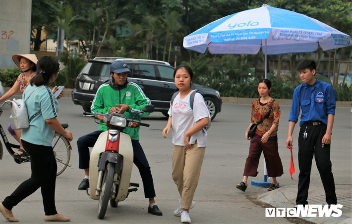 Một học sinh đi xe ôm đến trường được tình nguyện viên hướng dẫn khi gần đến giờ thi.