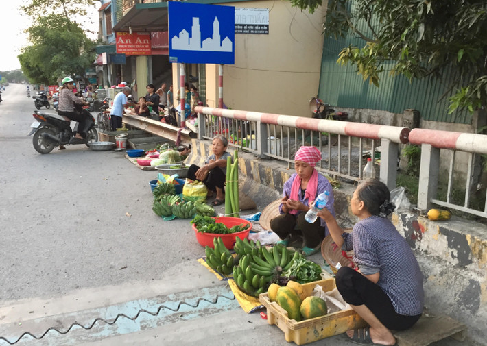 Việc người dân ngồi lấn chiếm lòng đường, mặt cầu tiềm ẩn nguy cơ tai nạn.