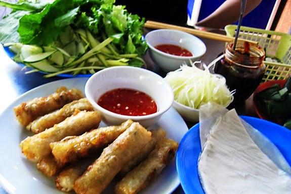 Ram cuốn cải. Địa chỉ: Đường Lê Duẩn, gần cửa hiệu Levi’s, trước trường Tiểu học Trần Cao Vân. Ram cuốn cải là một đặc sản của Đà nẵng. Nhân ram là một ít miến trộn với thịt và nấm mèo, chiên nóng rồi dọn thêm một ít nộm đu đủ, cà rốt và dưa cùng với một đĩa bánh tráng. Và dĩ nhiên là không thể thiếu rau sống và cải. Thêm 1 chén nước chấm hơi ngọt và cay. Một đĩa ram có 10 - 12 cái với giá từ 20.000 -30.000 đồng (Ảnh: Danangplus.net).