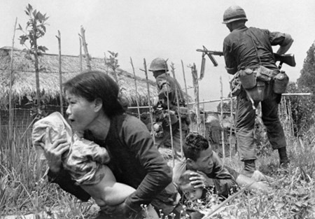 Hình ảnh xúc động cho thấy một bà mẹ Việt Nam cố gắng đưa con tới nơi an toàn dưới làn mưa bom bão đạn khi lính thủy đánh bộ Mỹ tràn vào làng Mỹ Sơn, Đà Nẵng để truy lùng quân giải phóng ngày 25/4/1965. Ảnh: Eddie Adams/AP.