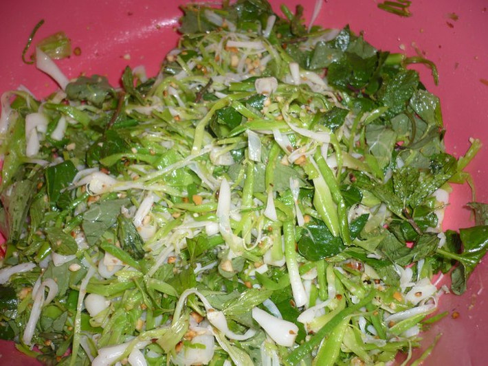 Ngâm tỏi khoảng 10 phút cho sạch nhựa, bắc lên bếp luộc vừa chín tới, vớt ra rổ để nguội và ráo nước. Cho tỏi cùng với đậu phộng, rau thơm vào trộn đều. Cho thêm một ít bột ngọt, đường để gỏi tỏi ngon hơn. Xong xuôi bày ra đĩa. Ăn gỏi tỏi với bánh tráng nướng mới đúng kiểu. Vị béo của bánh tráng quyện cùng vị thơm nồng nồng của tỏi không gì ngon bằng.