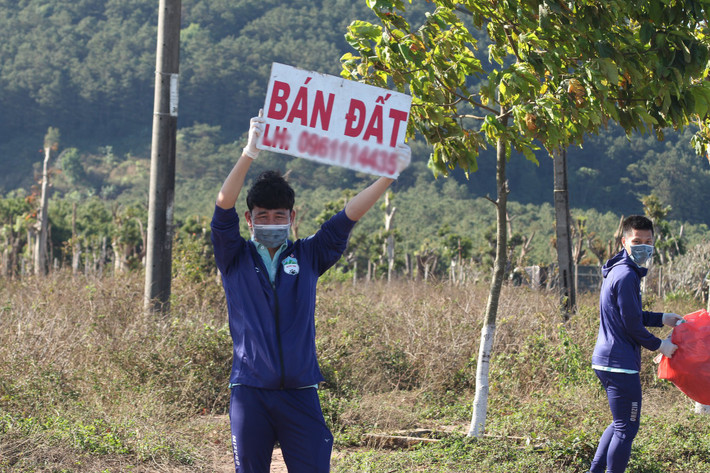 Nam cầu thủ hài hước cầm biểt "bán đất" rêu rao. Có lẽ mục đích của nam cầu thủ là đi nhặt rác, bán đất chứ không phải thăm quan sao?