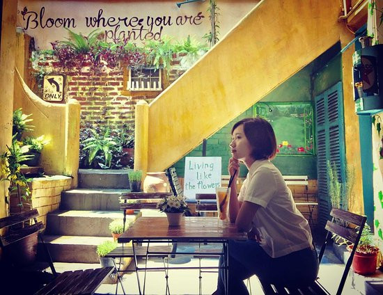 Ngay dưới chân cầu thang, chủ quán cũng tinh ý đặt chiếc bàn nhỏ xinh bên cạnh bức tường vàng phủ rêu.