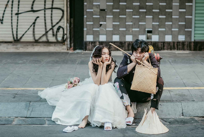 Chú rể chẳng diện suit nà nuột, bảnh bao, thay vào đó là bộ trang phục đen vá vải, vá báo chằng chịt. Cô dâu cũng không khá hơn là mấy khi diện chiếc váy trắng tinh khôi nhưng chắp vá đủ kiểu.