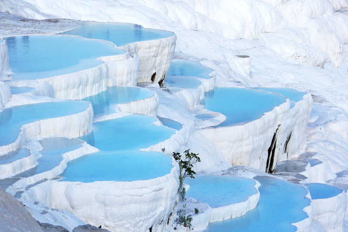 Lâu đài Bông “Cotton Castle” Pamukkale là một địa điểm check-in không thể bỏ lỡ khi đặt chân tới Thổ Nhĩ Kỳ. Nhìn từ xa, Pamukkale trắng xóa cứ như một ngọn núi tuyết, nơi đây được hình thành từ một dạng trầm tích lắng đọng do nước từ các suối nước nóng chứa nhiều canxi cacbonat chảy qua các gờ đá trong nhiều niên kỷ, tạo nên chuỗi những nhũ đá vôi trắng tinh xếp lớp như vỏ sò.
