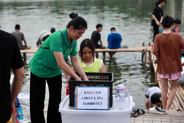 Các nhân viên nhắc nhở người dân không cho cá ăn tùy tiện mà có thể mua các túi cám nuôi cá với giá 10.000 đồng/túi.